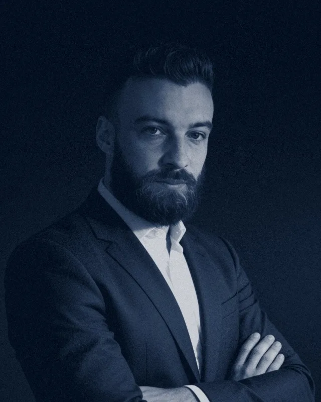 Avimar Machado, retrato editorial em duotone frio navy e prata, atravessado por um feixe de luz diagonal.